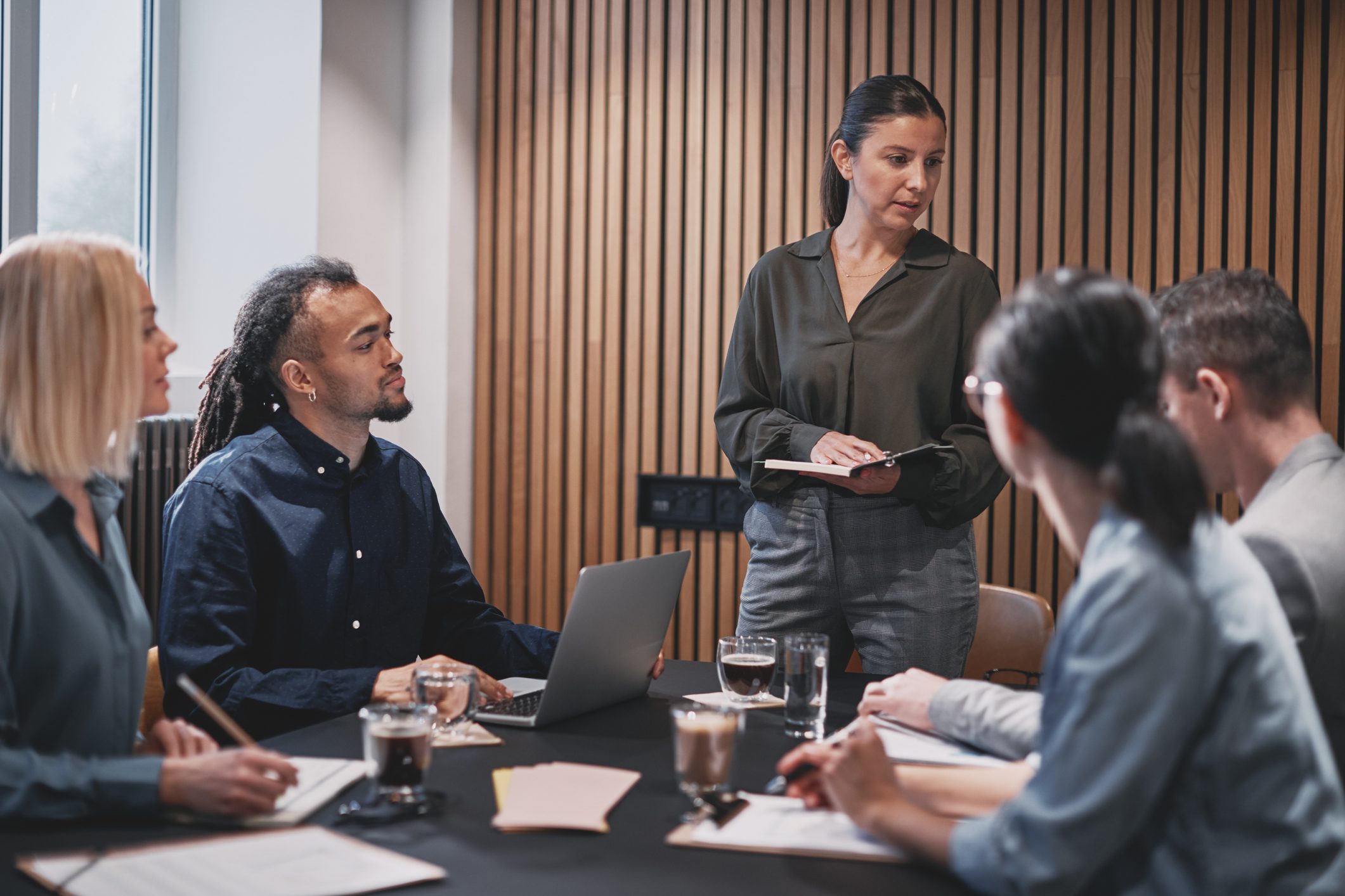 Young businesswoman having a meeting with her diverse staff around a table in an office boardroom